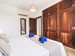 Ein Hotelzimmer mit einem Bett, einem großen Kleiderschrank, einem Spiegel und einer Hängelampe.