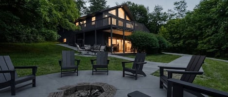 A modern house with a deck, outdoor seating, and a fire pit.