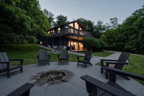 A modern house with a deck, outdoor seating, and a fire pit. - Travis Lodge | Hot Tub, Game Room & Trails (Logan)