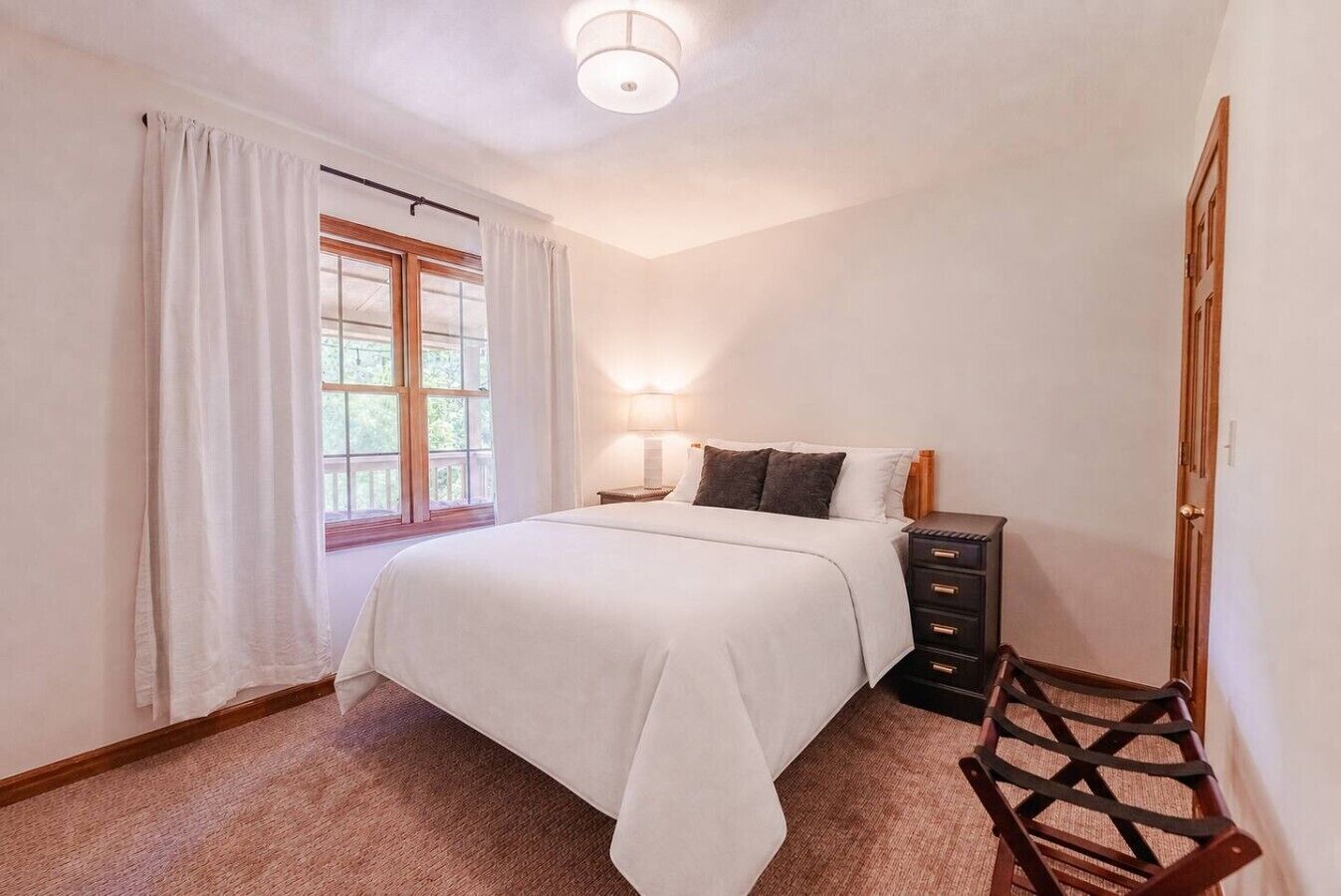 A bedroom with a bed, bedside table, lamp, and a chair.