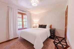 A bedroom with a bed, bedside table, lamp, and a chair. - Houston Lodge: HotTub, GameRoom, Pets, BBQ, Trails (Logan)