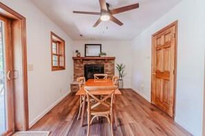 A dining area with a wooden table and chairs, a fireplace, and a ceiling fan. - Houston Lodge: HotTub, GameRoom, Pets, BBQ, Trails (Logan)
