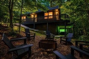 En hytte med terrasse, udendørs møbler og bålsted.