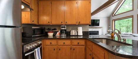 Une cuisine moderne avec des meubles en bois, des appareils en acier inoxydable et une grande fenêtre qui laisse entrer la lumière naturelle.