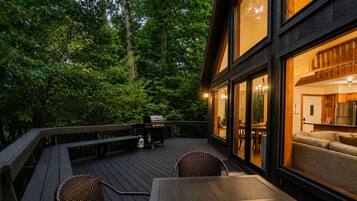 Eine Terrassenausstattung mit Tisch, Stühlen, Grill und Blick ins Innere.