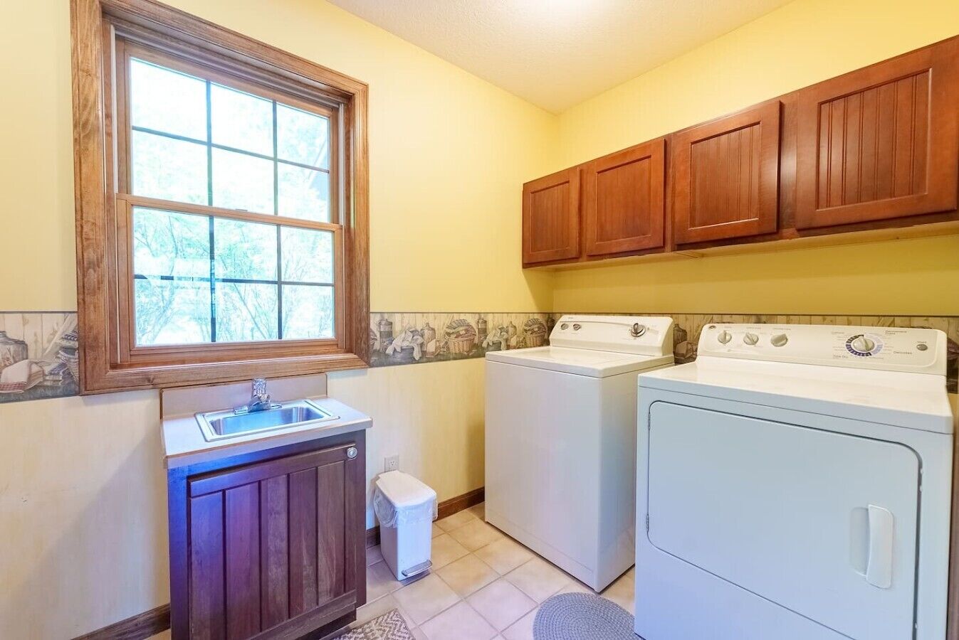 A compact laundry room with a washing machine, dryer, and sink.