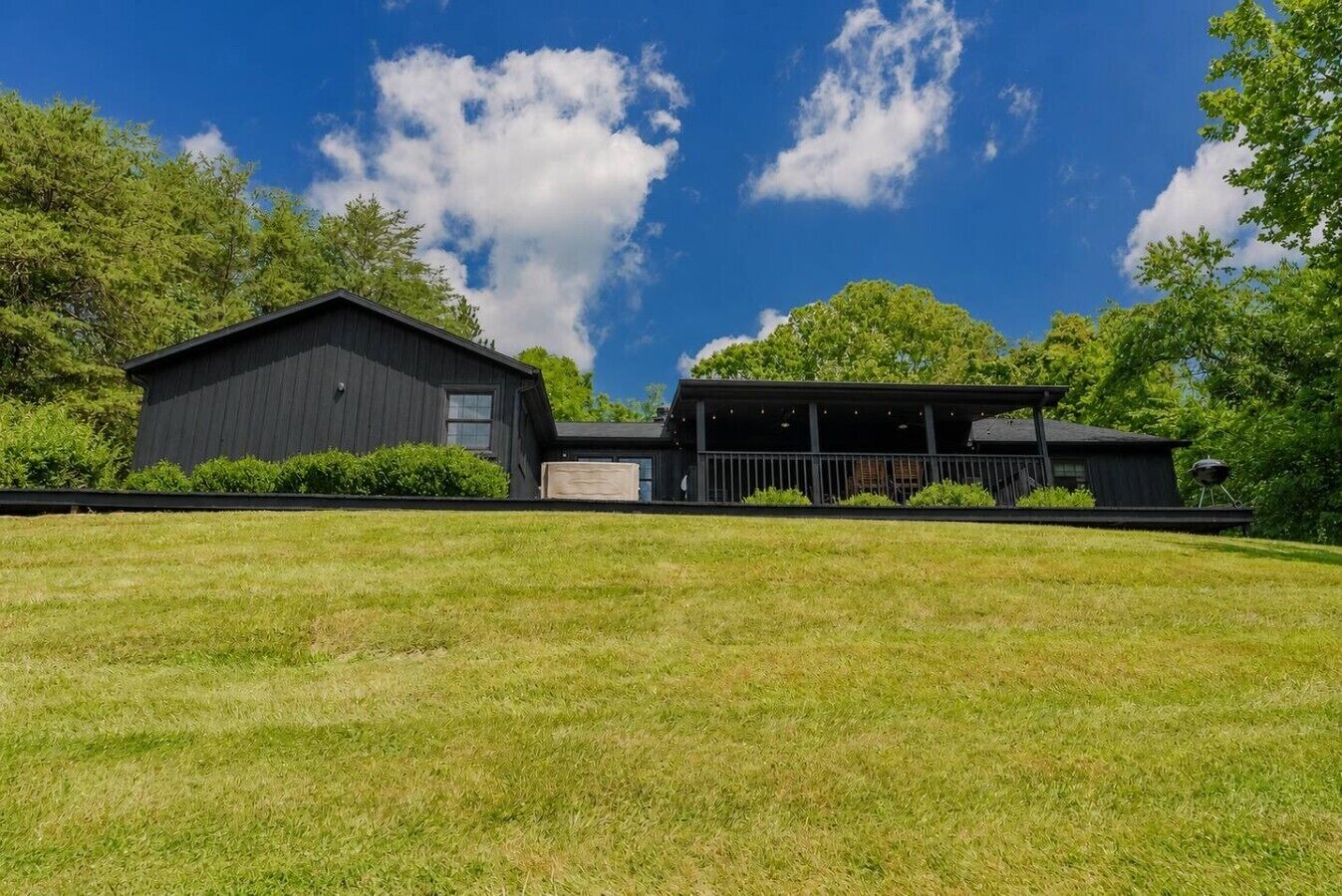 Uma casa moderna de dois andares com varanda coberta e um gramado amplo.