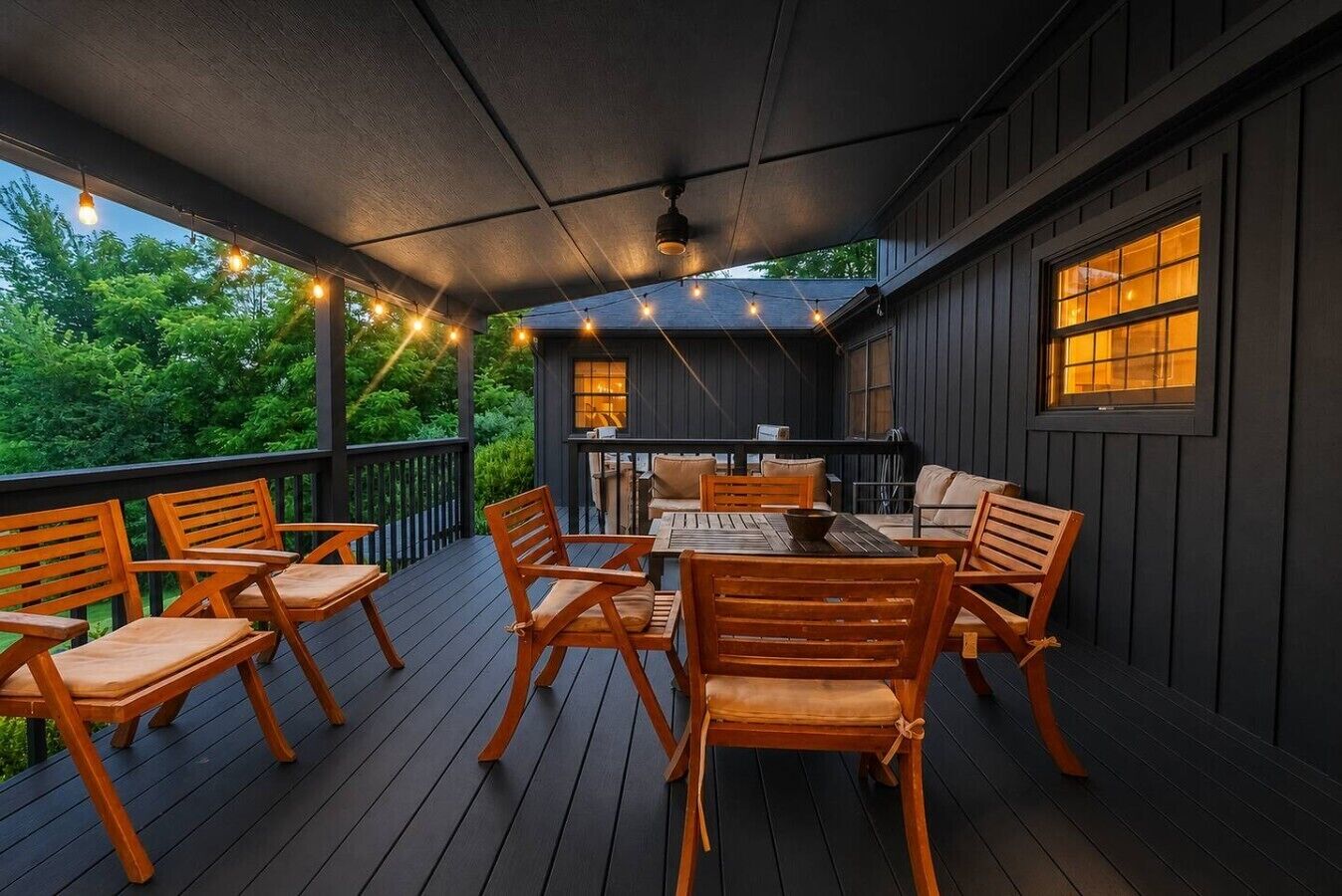 An outdoor deck with wooden furniture and string lights.