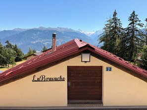 A building with a red roof, a wooden door, and the name 'LaBravache' on the wall. - La Bravache - Cozy chalet with an exceptional view (Savièse)