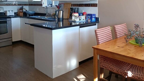 Een moderne keuken met witte kasten, een centraal eiland en een eethoek met gestreepte stoelen.