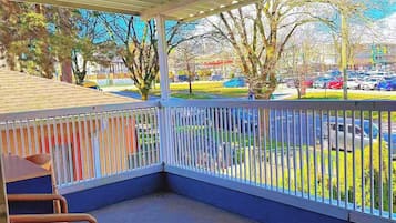 A covered outdoor seating area with a view of a parking lot and trees.