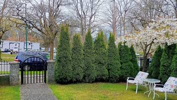 A pathway leading to a gated area with a gazebo, surrounded by neatly trimmed hedges and trees.