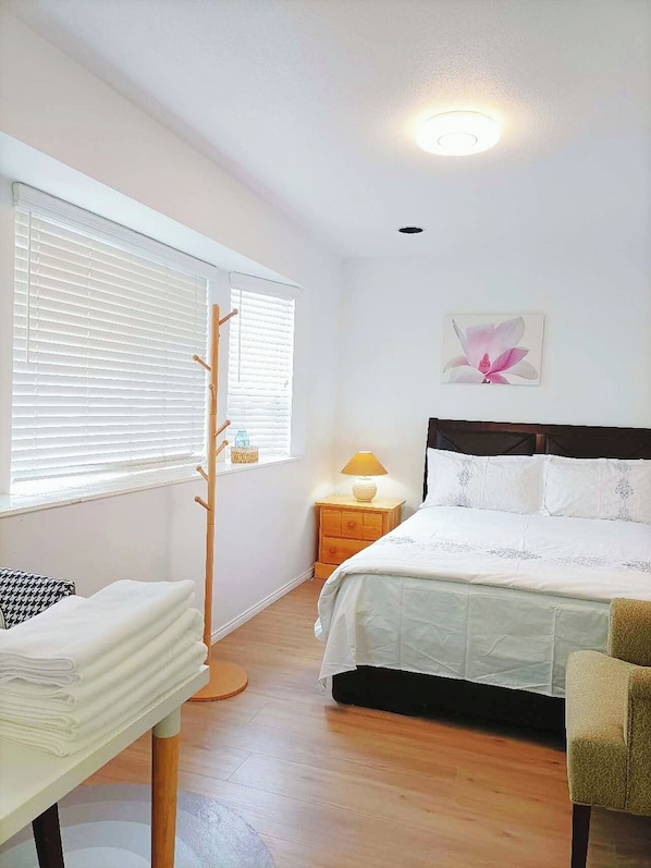 A bedroom with a bed, bedside table, lamp, and a window with blinds.