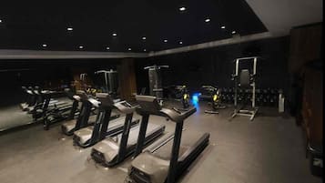 Un gimnasio con cintas de correr, máquinas de pesas y un espejo grande.