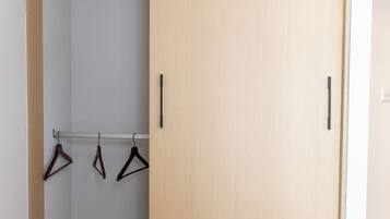 Et walk-in closet med trædøre, en bøjlestang og et knagered.