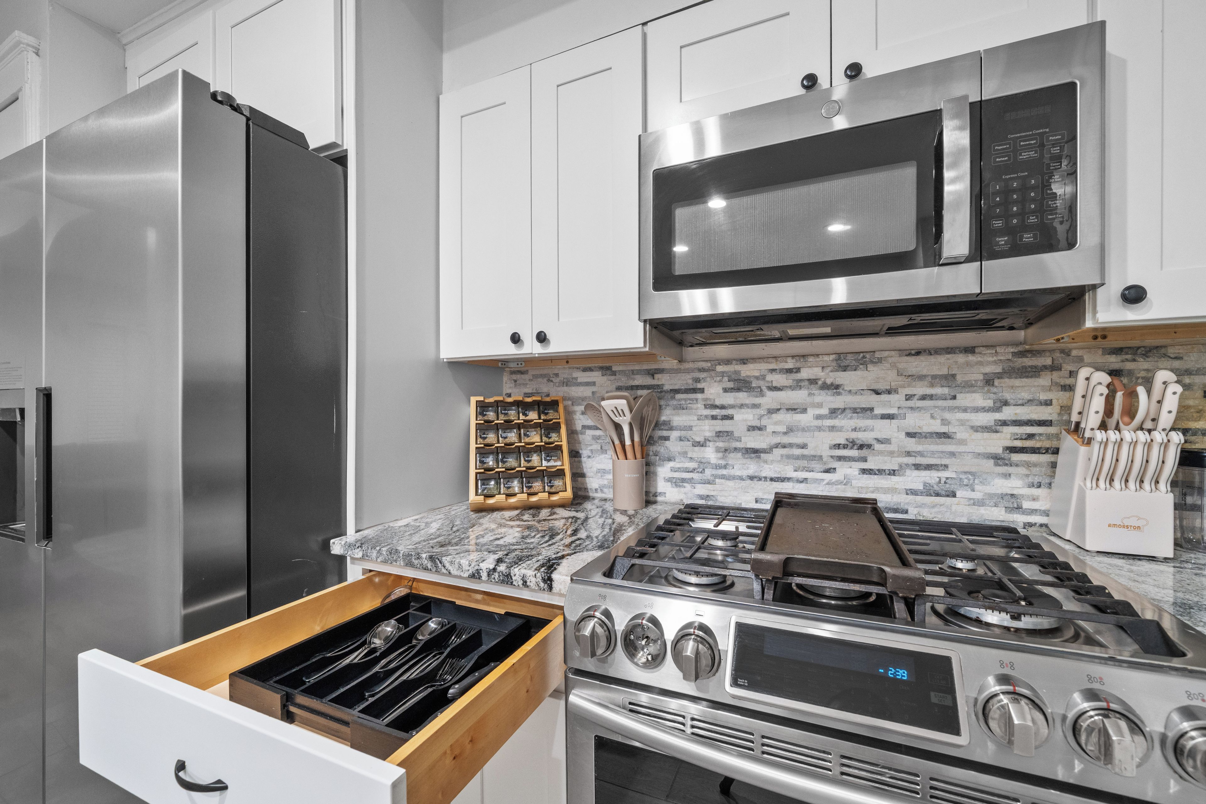 A modern kitchen with stainless steel appliances, a microwave, and a gas stove.