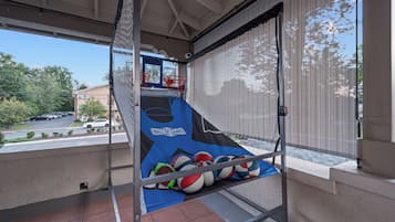 Una cancha de baloncesto con una red, un aro de baloncesto y una alfombra azul con el texto 'Hall of Games'.