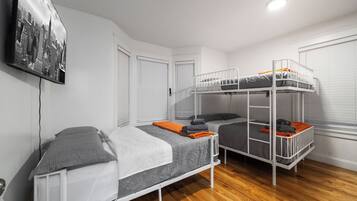 Una habitación con literas, una puerta, una ventana con persianas y un cuadro colgado en la pared.