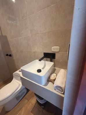 Un baño con un lavamanos blanco, un inodoro y una toalla en un estante.