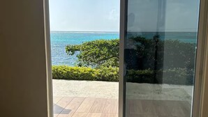 Une pièce dotée d’une grande porte-fenêtre coulissante qui donne sur un patio offrant une vue sur l’océan.