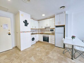 A compact kitchen with a washing machine, oven, microwave, and a refrigerator. - Apartamento Alba 4 by Interhome (Cartagena)