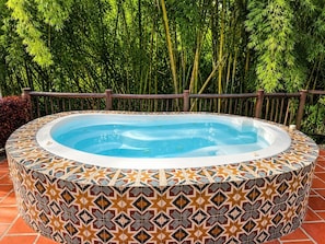 A hot tub with a patterned tile surround, set against a bamboo backdrop.