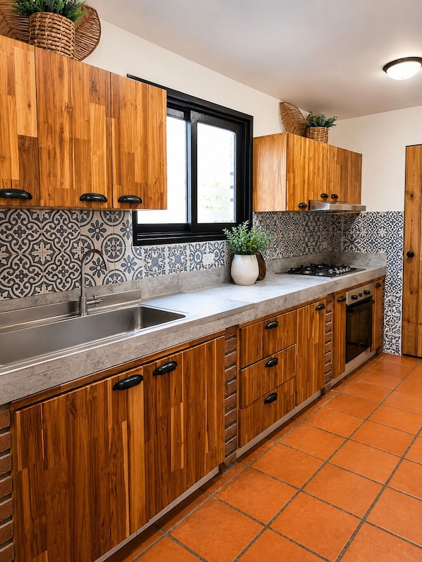 A kitchen with wooden cabinets, a stainless steel sink, and a tiled backsplash.