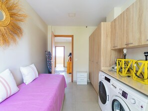 Ein gemütliches Schlafzimmer mit Bett, Waschmaschine und einer kleinen Küchenzeile.
