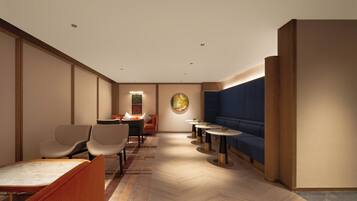A hotel lobby with seating areas, a reception desk, and a wall-mounted artwork.