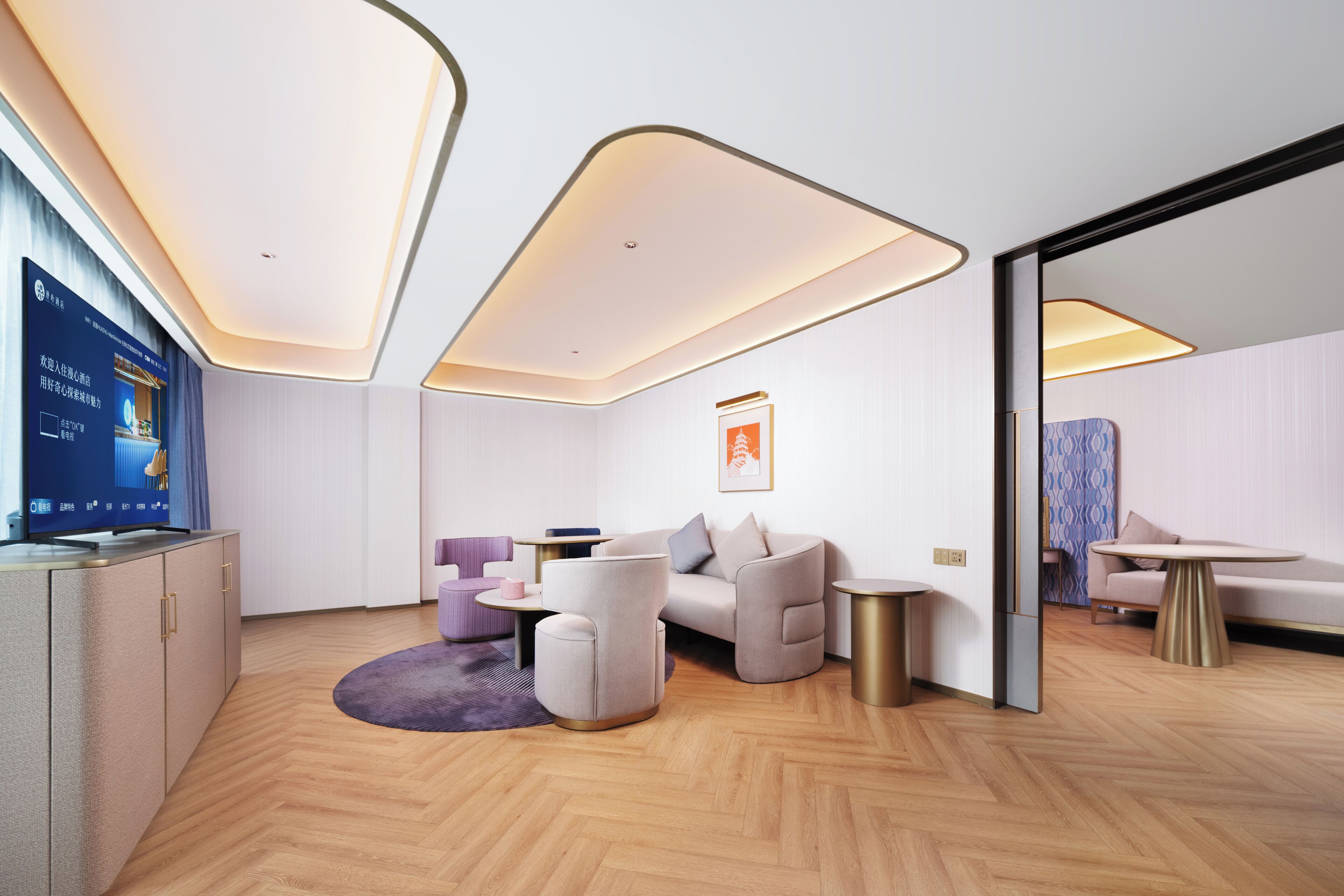 A modern hotel room with a flat-screen TV, a sofa, a coffee table, and a small side table.