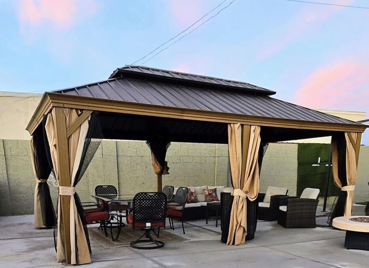 A covered outdoor seating area with chairs and sofas, a table, and a pergola structure.