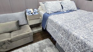Ein Schlafzimmer mit Bett, Nachttisch, Sofa und Teppich.