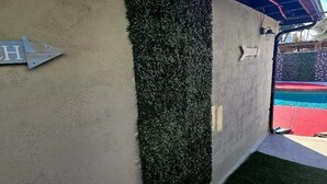 Eine Wand mit vertikalem Garten, ein Metallschild mit Pfeil und ein Blick auf einen roten und grünen Spielbereich.