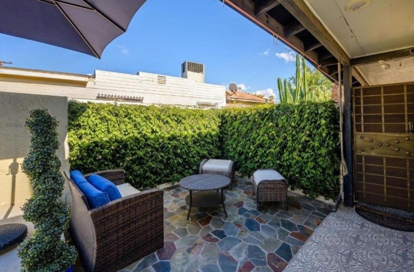 Une terrasse extérieure avec des meubles en osier, un sol en pierre et un mur végétal.