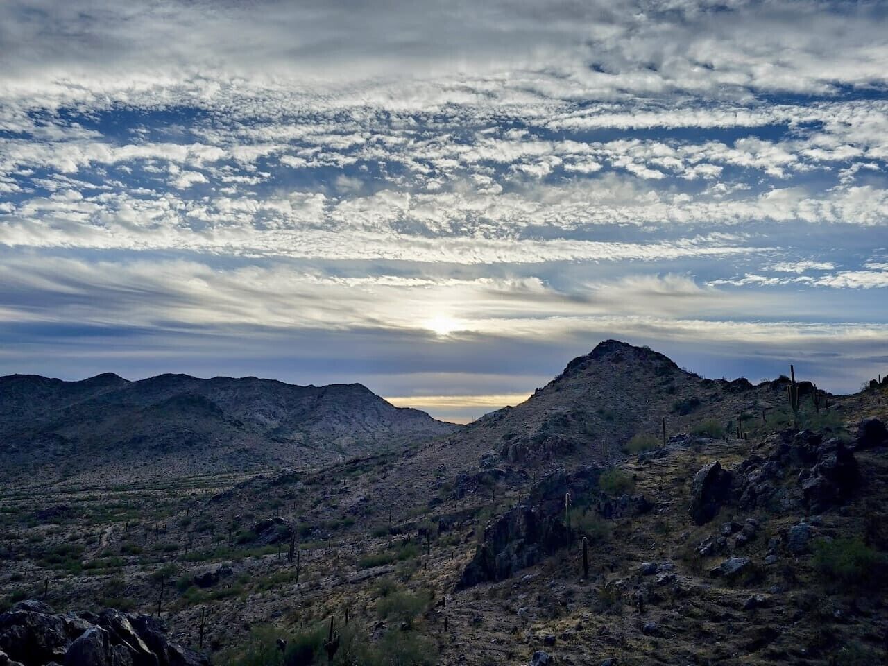 A mountainous landscape with a clear sky and the sun setting or rising.