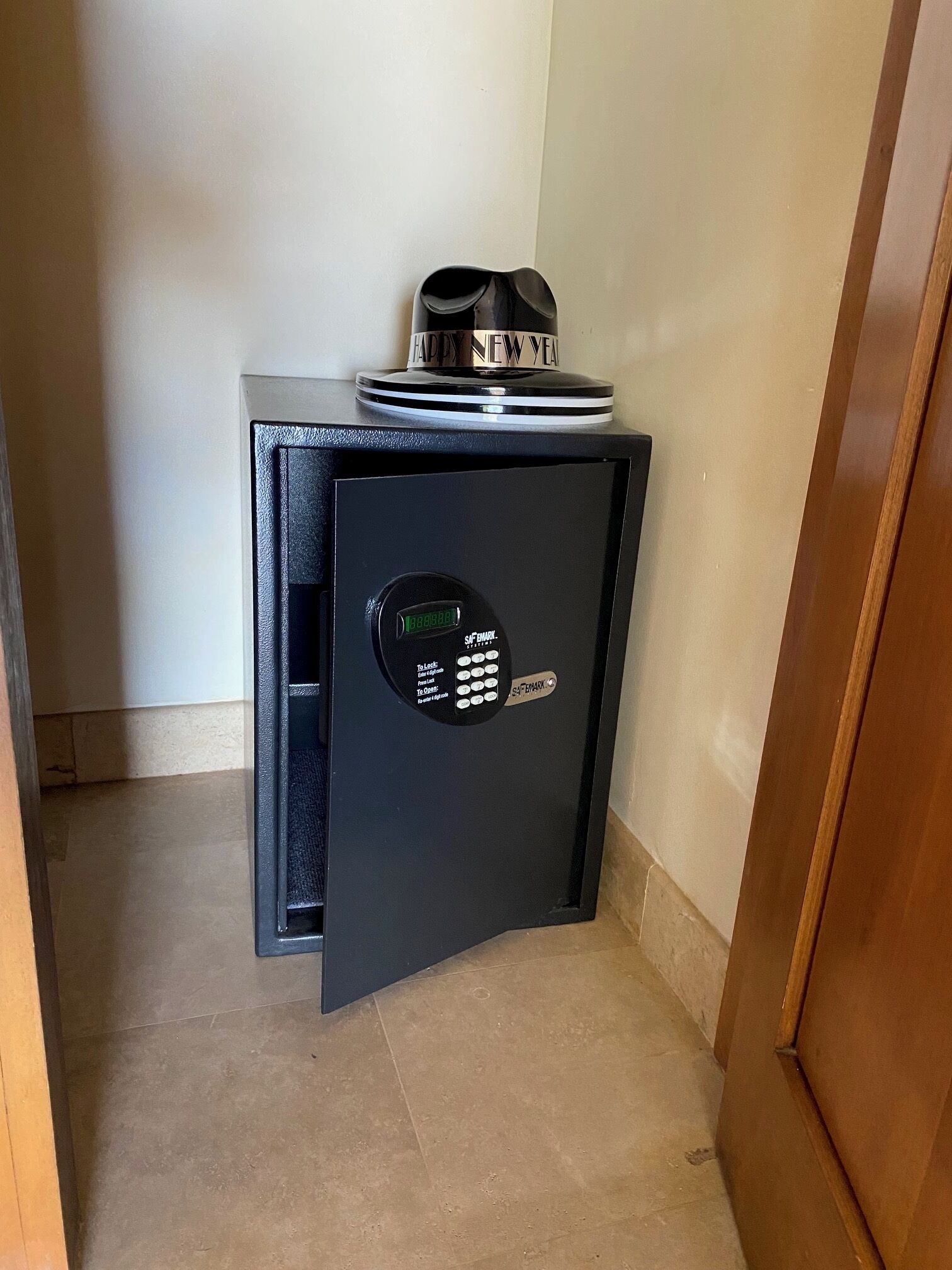 A black safe with a digital keypad and a 'Happy New Year' sign on top.