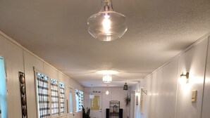 En hall med ett matbord och stolar, en hängande lampa och en dörr längst in.