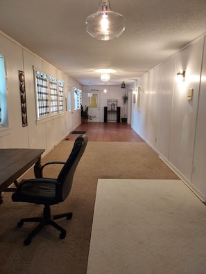 Un couloir avec une table à manger et des chaises, un luminaire suspendu et une porte au fond.