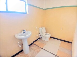 Un baño pequeño con lavamanos, inodoro y ventana.