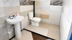 Um banheiro com pia branca, vaso sanitário e azulejos com padrão marmorizado.