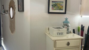 A hallway with a white wall, a framed picture, a mirror, and a small white cabinet with drawers. - House with a garden in Santa Teresa di Gallura (Santa Teresa di Gallura)