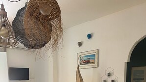 A dining area with a table set for four, white chairs, a woven hanging light fixture, and a wall-mounted picture. - House with a garden in Santa Teresa di Gallura (Santa Teresa di Gallura)