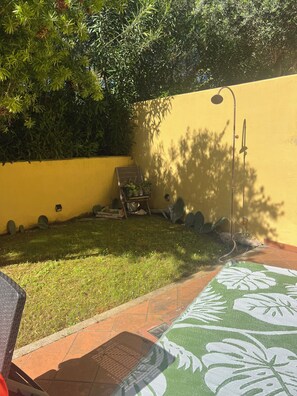A patio area with a yellow wall, a green lawn, and a patterned mat. - House with a garden in Santa Teresa di Gallura (Santa Teresa di Gallura)