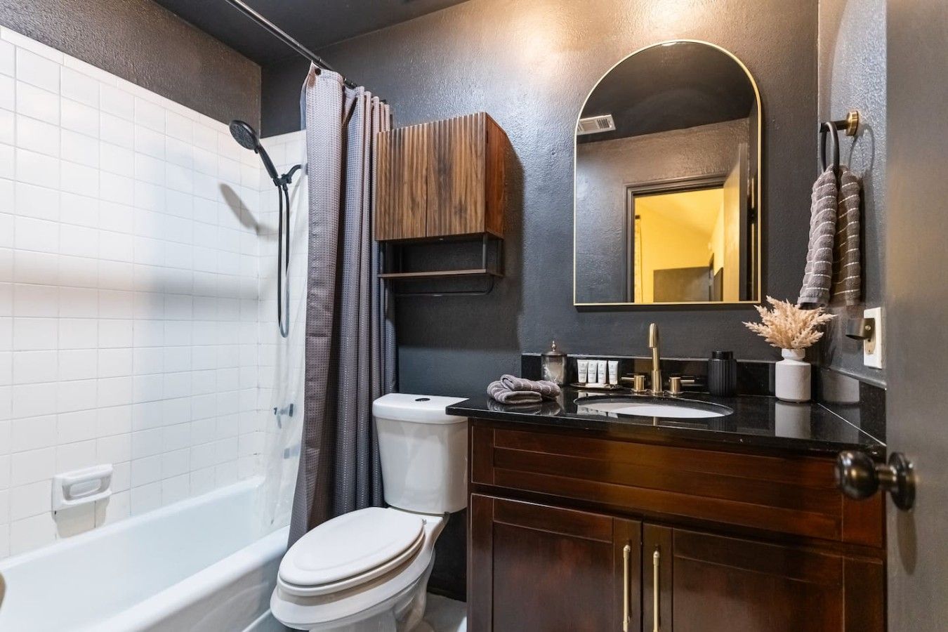 A modern bathroom with a bathtub, toilet, vanity, and a large mirror.