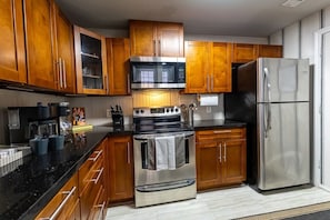 Eine Küche mit Holzausstattung, einem Edelstahlbackofen, einer Mikrowelle und einem Kühlschrank.