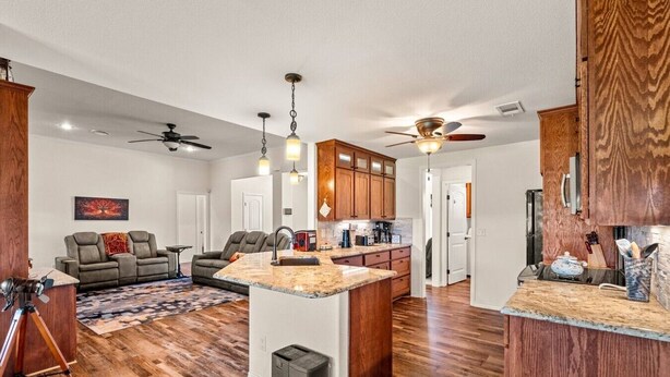 A modern kitchen with wooden cabinets, a central island, and a dining area with a sofa. - Family Country Home | Gaming, Workspace, Yard (Terrell)