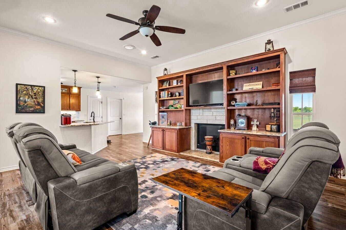A living room with a fireplace, a ceiling fan, and a TV.