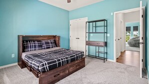 A bedroom with a bed, a ceiling fan, a wardrobe, and a glass shelving unit. - Family Country Home | Gaming, Workspace, Yard (Terrell)
