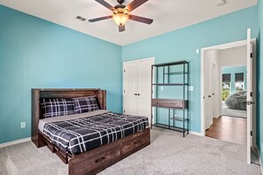 A bedroom with a bed, a ceiling fan, a wardrobe, and a glass shelving unit. - Family Country Home | Gaming, Workspace, Yard (Terrell)
