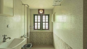 A bathroom with a bathtub, a window with bars, and a towel rack. - Sukumara Homestay Unique Eco Luxury Mud and Bamboo Beachfront Villa (Thrissur)